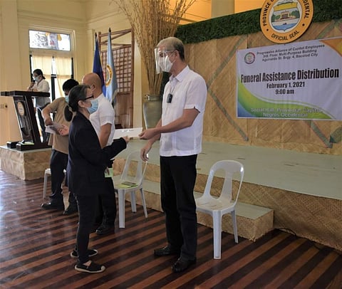 NEGROS. Governor Eugenio Jose Lacson hands the P30,000 cash to a Capitol employee who is a beneficiary of the Pace funeral assistance program. (Contributed photo)