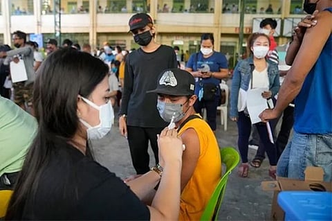 MANILA. A resident looks at the syringe after being inoculated with the AstraZeneca Covid-19 vaccine at a vaccination center in Quezon City, Philippines on Tuesday, January 11, 2022. (AP)