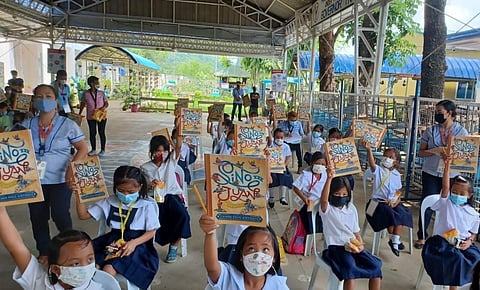 PROMOTING READING. Grade 1 students from Pinugay Elementary School in Baras, Rizal eagerly receive the books created by the Center for Art, New Ventures and Sustainable Development and distributed by Global Business Power Corp. through subsidiary, PH Renewables Inc. / CONTRIBUTED