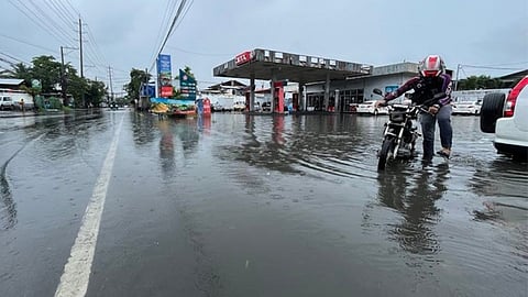 Protecting PROPERTY. A man pushes his motorcycle out of the flooded portion of C. Padilla Street in Cebu City near a gasoline station on Wednesday, Oct. 26, 2022.