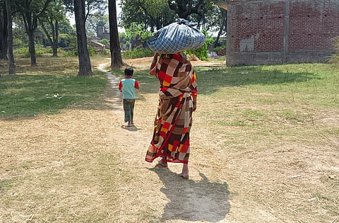 भैंस के लिए खेत से चारा लेकर घर की ओर जाती सुरसती देवी, और साथ में उनकी पोती प्रतिभा