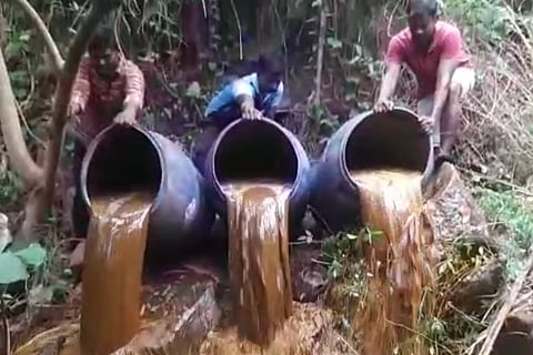 Representative image of Illicit liquor being poured out of barrels.