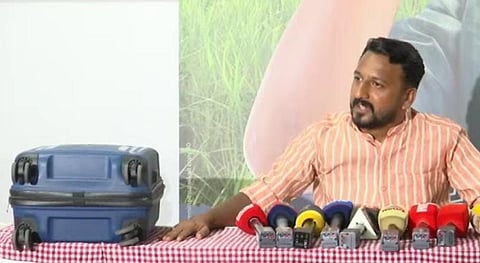 Rahul Mamkootathil attending a press conference with a blue trolley bag