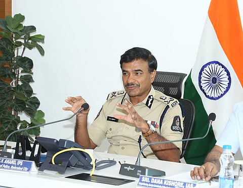 Hyderabad Commissioner of Police CV Anand in uniform sitting at a desk speaking into a mic. The Indian national flag is in the background. 