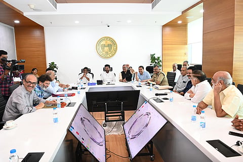 Telangana CM Revanth Reddy and Deputy CM Mallu Bhatti Vikramarka in a meeting with Tollywood producers Dil Raju, Suresh Babu, and Allu Aravind, and directors K Raghavendra Rao, Trivikram Srinivas and others. They are seated in a conference room with screens in between the tables. 