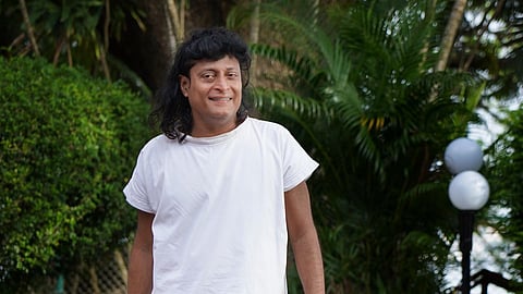 Bobby Chemmanur in a white attire walking along a paved pathway