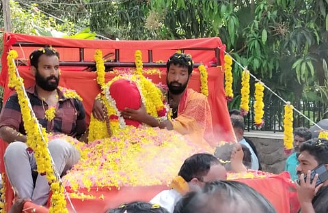 Devotees accompany the flower-decorated mortal remains of Gopan Swami on the way to the samadhi site, surrounded by prayers and rituals. 
