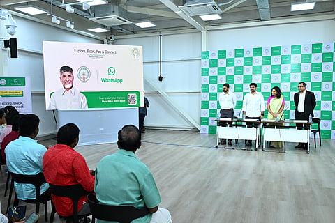 This image shows an event highlighting a WhatsApp-based governance initiative. The display board includes a portrait of Andhra Pradesh Chief Minister Chandrababu Naidu, along with the Andhra Pradesh government logo and the WhatsApp logo. 

The banner reads, "Explore, Book, Pay & Connect with GoAP - Mana Mitra." There's a QR code for scanning and starting a chat, along with a contact number labeled "Mana Mitra: 95532 00009."

In the foreground, seated participants face the presentation, while a group of individuals including Minister Nara Lokesh stands near a desk, leading the event. The setting is formal, with a backdrop featuring a logo in a repeating pattern.