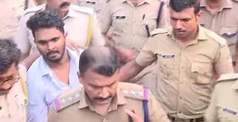 Police officers in khaki uniforms with Afan in a light blue shirt during the evidence collection process. 