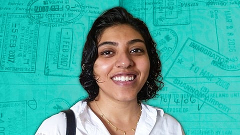 Former Columbia doctoral candidate Ranjani Srinivasan in a white shirt and smiling. There is a greenish-blue stylised background behind overlayed with generic image of passport stamps. 