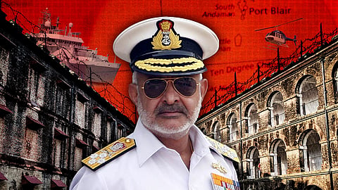 **Alt text:**  
An Indian Navy officer wearing a white uniform, medals, and a peaked cap with the Indian emblem stands in the foreground. He has a stern expression and wears aviator sunglasses. In the background is a collage featuring the historic Cellular Jail in Port Blair, barbed wire, a naval ship, a helicopter, and a red-toned map of the Andaman and Nicobar Islands with "Port Blair" and "Ten Degree Channel" marked. The visual conveys themes of military presence, security, and historical significance.