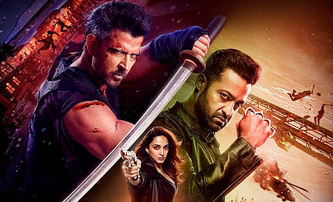 Promotional poster for the action film War 2, featuring Hrithik Roshan holding a blood-stained sword in a combat stance on the left, N. T. Rama Rao Jr. (Jr NTR) with clenched fists on the right, and Kiara Advani in the center aiming a gun at the viewer, with an intense battle scene and explosions in the background.