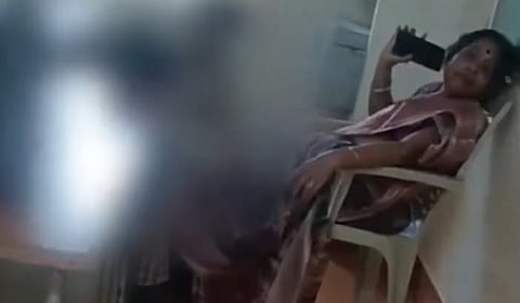 Teacher resting on her chair while two students massage her feet. 