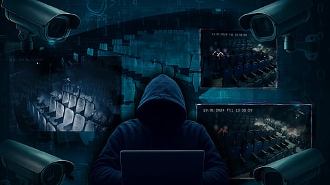 An image of a hacker wearing a hoodie in the middle surrounded by blurred screenshots of CCTV footage from movie theatres