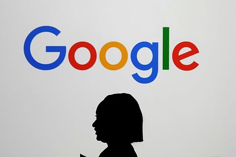 A woman walks by a giant screen with a logo at an event at the Paris Google Lab on the sidelines of the AI Action Summit in Paris, on Feb. 9, 2025. 