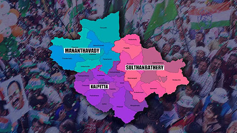 A colour-coded map of Wayanad district overlaid on a blurred background of a large crowd holding Congress flags. The map is divided into three assembly constituencies: Mananthavady (blue shades) in the north-west, Sulthan Bathery (pink shades) in the east, and Kalpetta (purple shades) in the south-west.