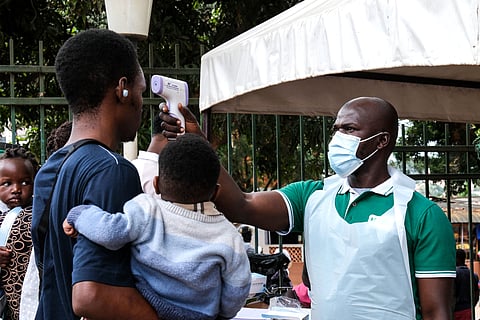 A health official uses a thermometer to screen people in front of Kibuli Muslim Hospital in Kampala, Uganda, Saturday, May 16, 2026. (AP Photo/ Hajarah Nalwadda)

