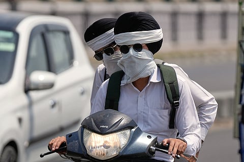 Commuters on a two-wheeler have their faces covered to protect themselves from the intense summer heat in Jammu, India, Tuesday, May 19, 2026. (AP Photo/Channi Anand)
