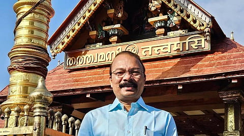 Image of former president of Travancore Devaswom Board P S Prasanth standing in front of Sabarimala temple