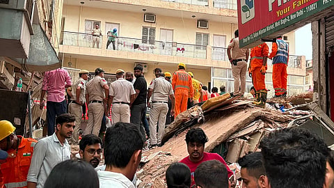 Search and rescue operations at Satya Niketan. People standing on and around the debris