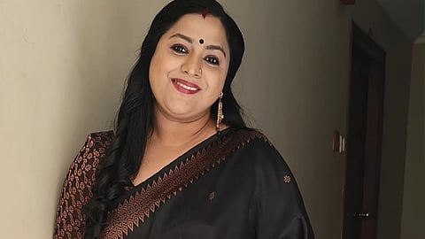 Actor Lakshmi Priya in a black saree facing the camera