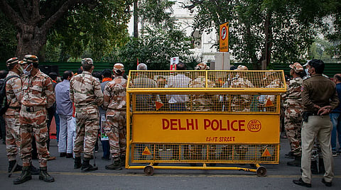 Representative image of Delhi Police personnel and paramilitary forces standing behind a yellow police barricade on a street in New Delhi.