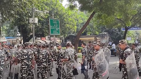 Personnel wearing uniform carrying batons and shields walking along the streets of Delhi
