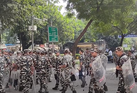 Personnel wearing uniform carrying batons and shields walking along the streets of Delhi