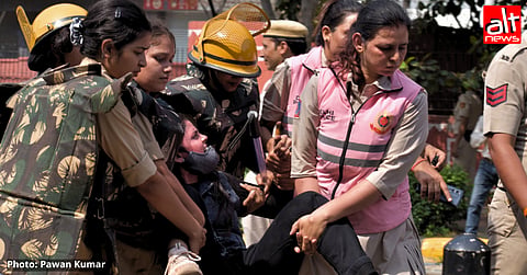 A woman being dragged away by five women police personnel