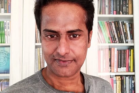 Ravi Nair standing in front of a book shelf