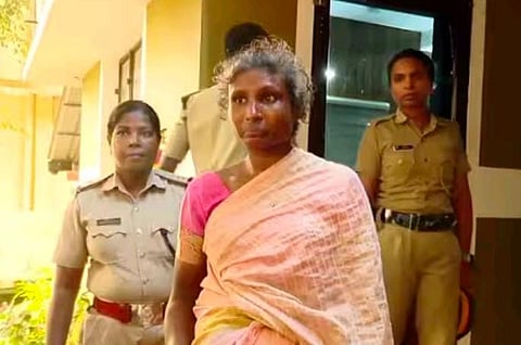 Manju in a light pink saree walks out of a building accompanied by police officers.