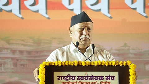 RSS chief Mohan Bhagwat speaking at a podium decorated with yellow marigold garlands during an event in Nagpur.