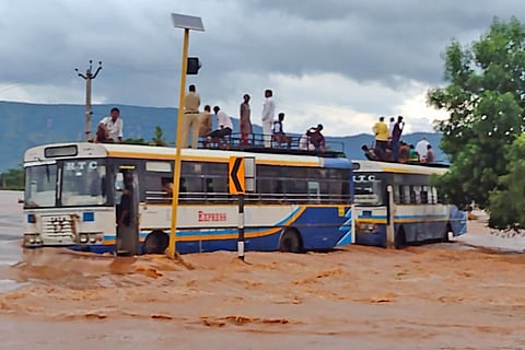 People standing on top of buses amid raging floods in Andhra Pradesh