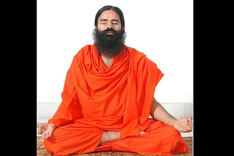 Holding a book, Ramdev poses for a photo