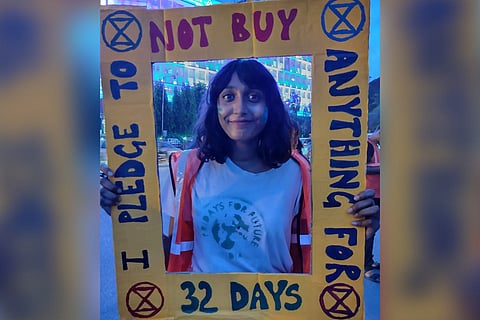 Activist Disha Ravi holding a pledge placard and smiling at camera