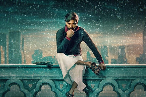 Dhanush in black shirt and white dhoti sitting on a wall in Jagame Thandhiram poster