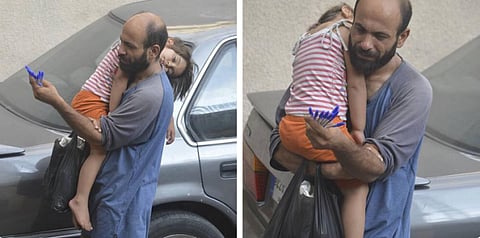 Photos of refugee selling pens while carrying his sleeping daughter sparks online fundraising campaign