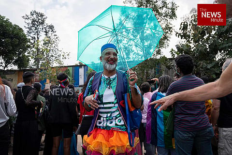 A person with a blue umbrella and a colourful outfit at Bengaluru’s Ride with Pride