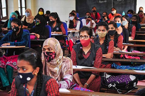 Rows of students sitting in a classroom while wearing masks