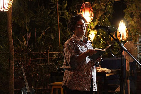 An artist is seen performing a poetry piece in the image.