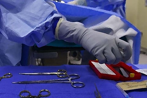 Representative image of a gloved hand picking up medical equipment