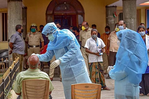 A health worker in PPE suit collecting nasal swab samples from a man for coronavirus test