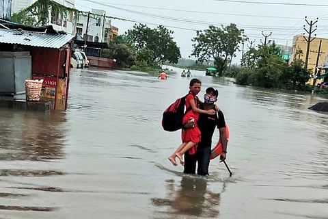 Photo of a relief personnel rescuing a girl in Warangal 