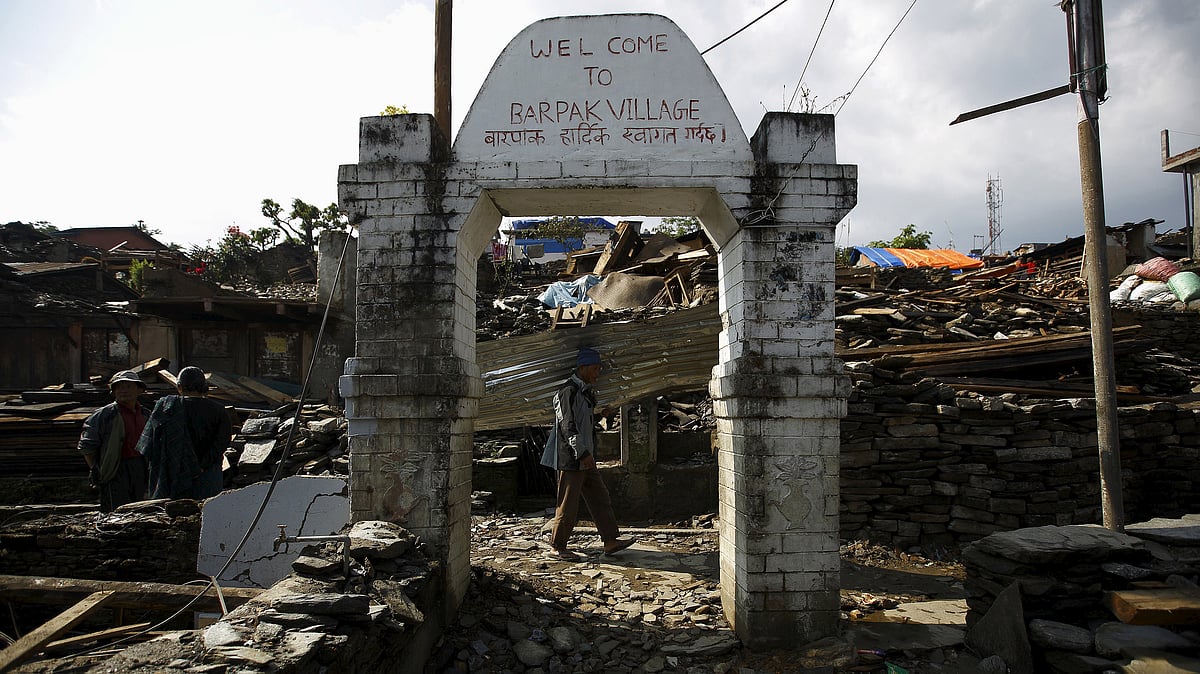 An earthquake victim, carrying a tin roof to rebuild a house, walks along the entrance gate of Barpak village at the epicenter of the April 25 earthquake in Gorkha district, Nepal, May 21, 2015. (Photo: Reuters)