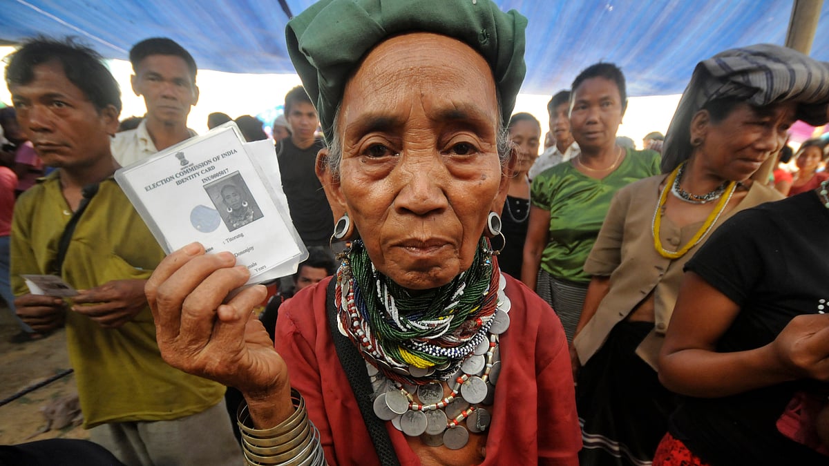 A Bru refugee wearing traditional ornaments displays her voting card as she and others wait to cast their ballots at Thamsapara relief camp in Tripura on April 1, 2014. 