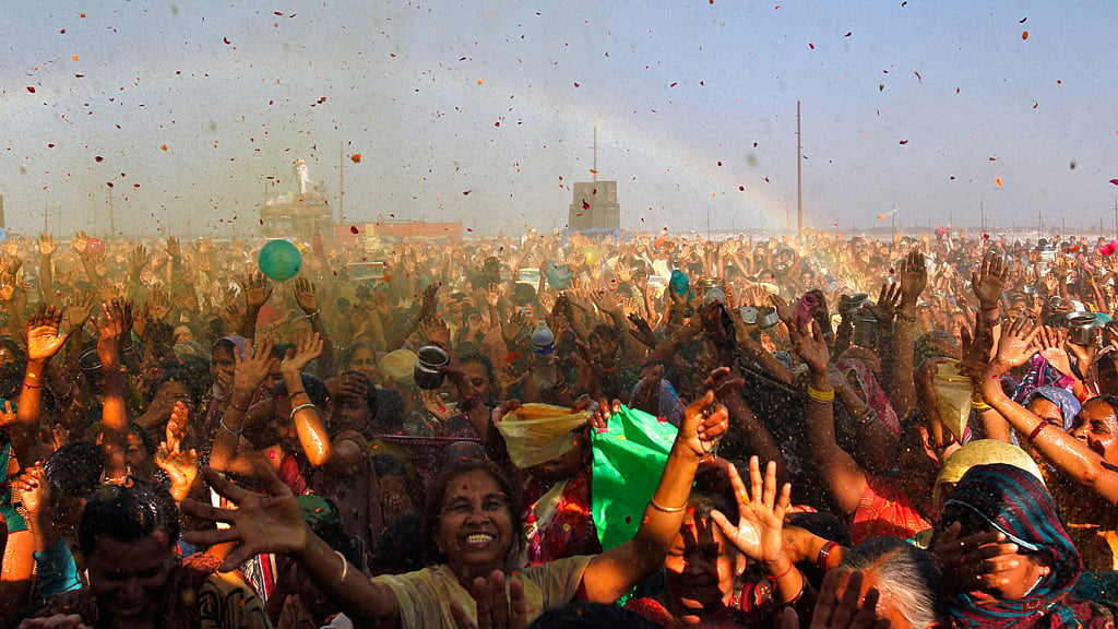 Devotees raise their hands to receive coloured holy water from a priest on the banks of the river Ganges in Allahabad. (Photo: Reuters)