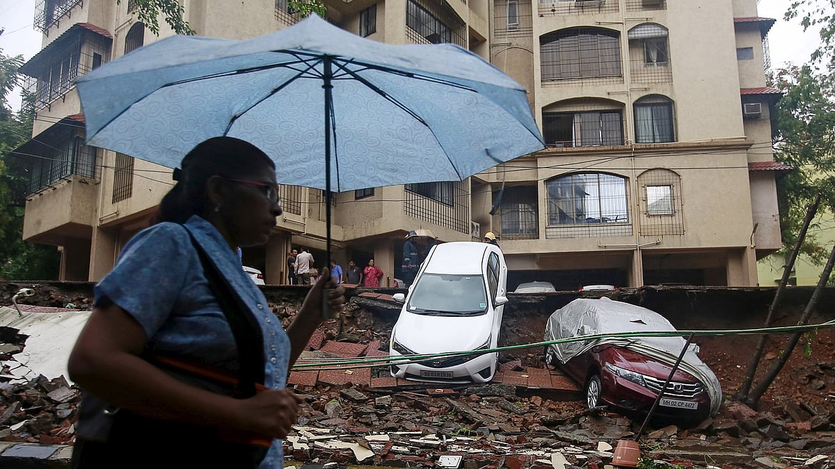 A woman walks past the remains of a wall that collapsed due to heavy rains in Mumbai on July 21, 2015. (Photo: Reuters)