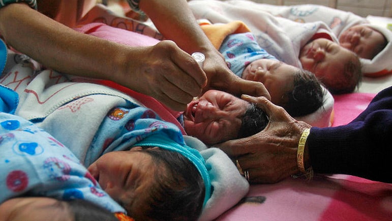 A medical worker administers polio drops to an infant at a hospital.&nbsp;