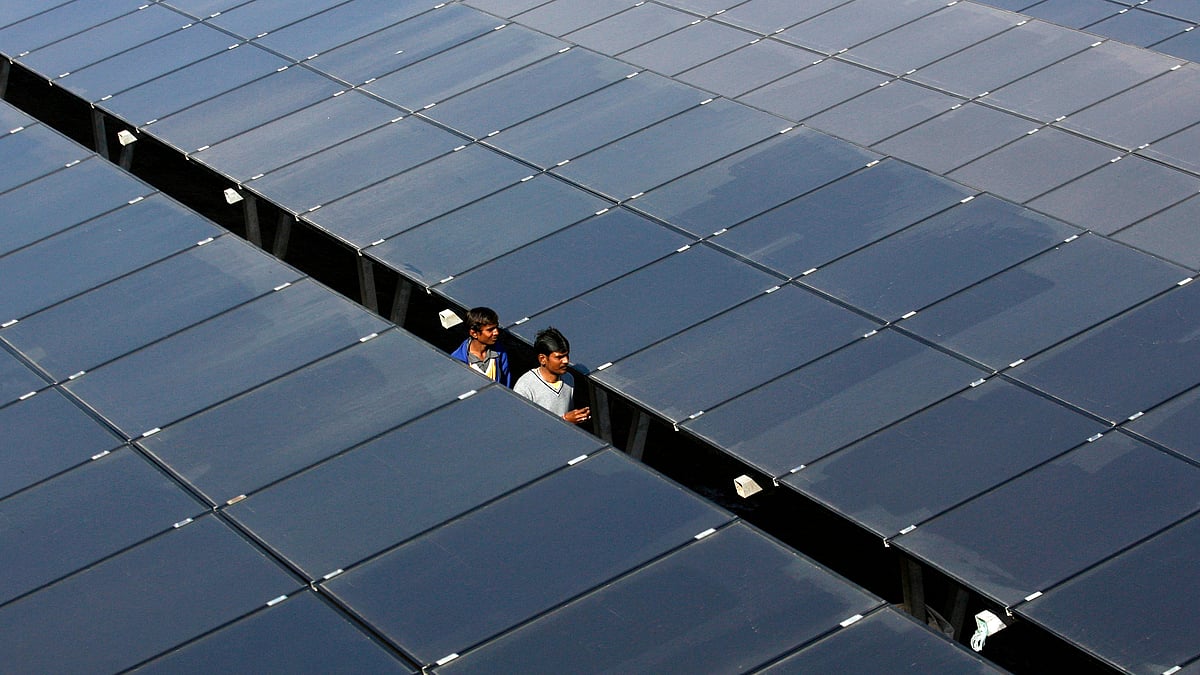 Workers walk between rows of solar photovoltaics, inside a solar power plant at Raisan village near Gandhinagar. (Photo: Reuters)