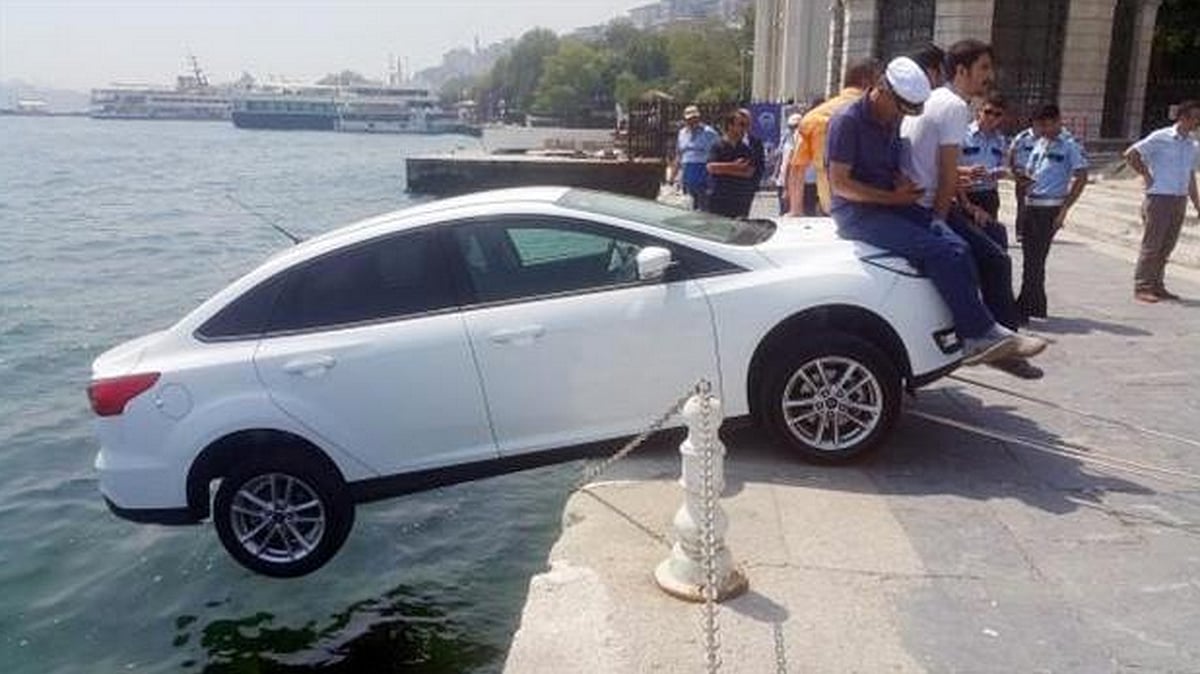 Local residents sit on the hood of a car, saving it from falling into river Bosphorus. (Photo: YT screengrab)